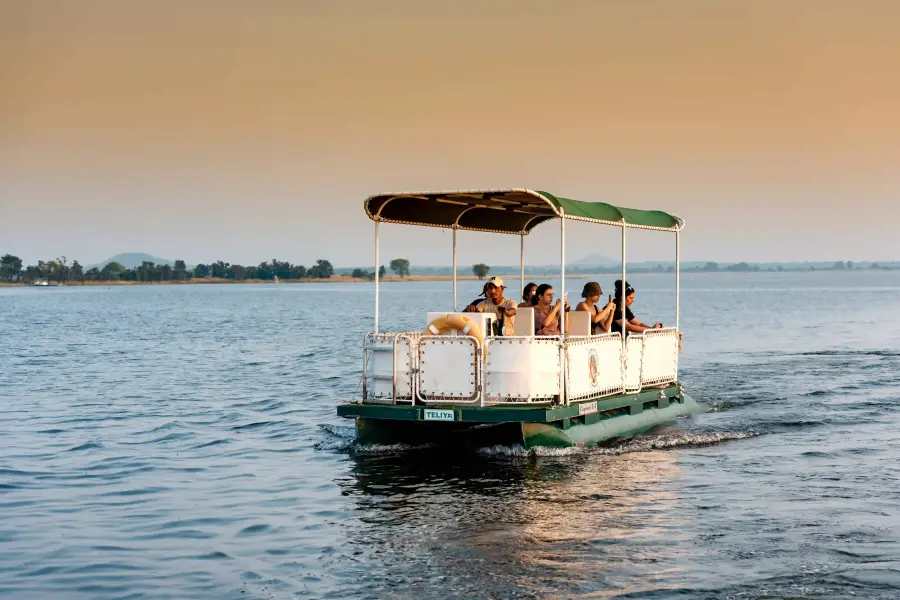 Guests on a pontoon boat safari across the reservoir at golden hour