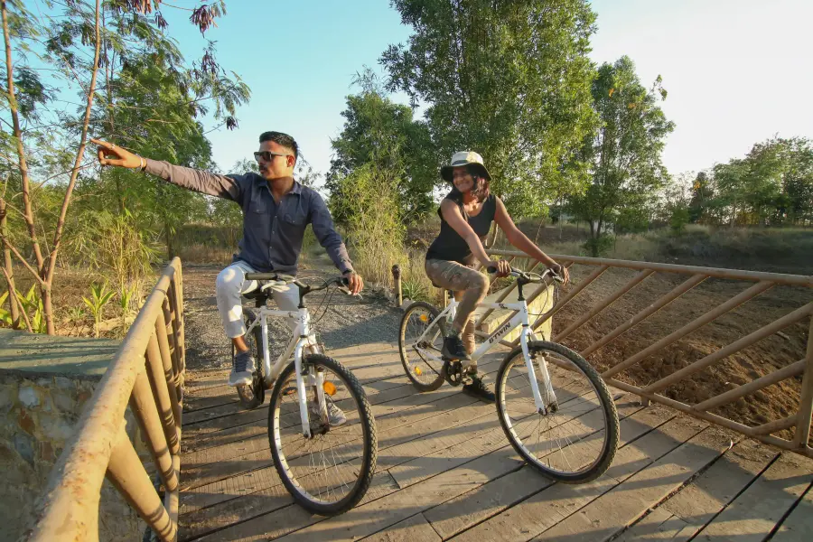 Guests cycling the camp trail across a wooden bridge