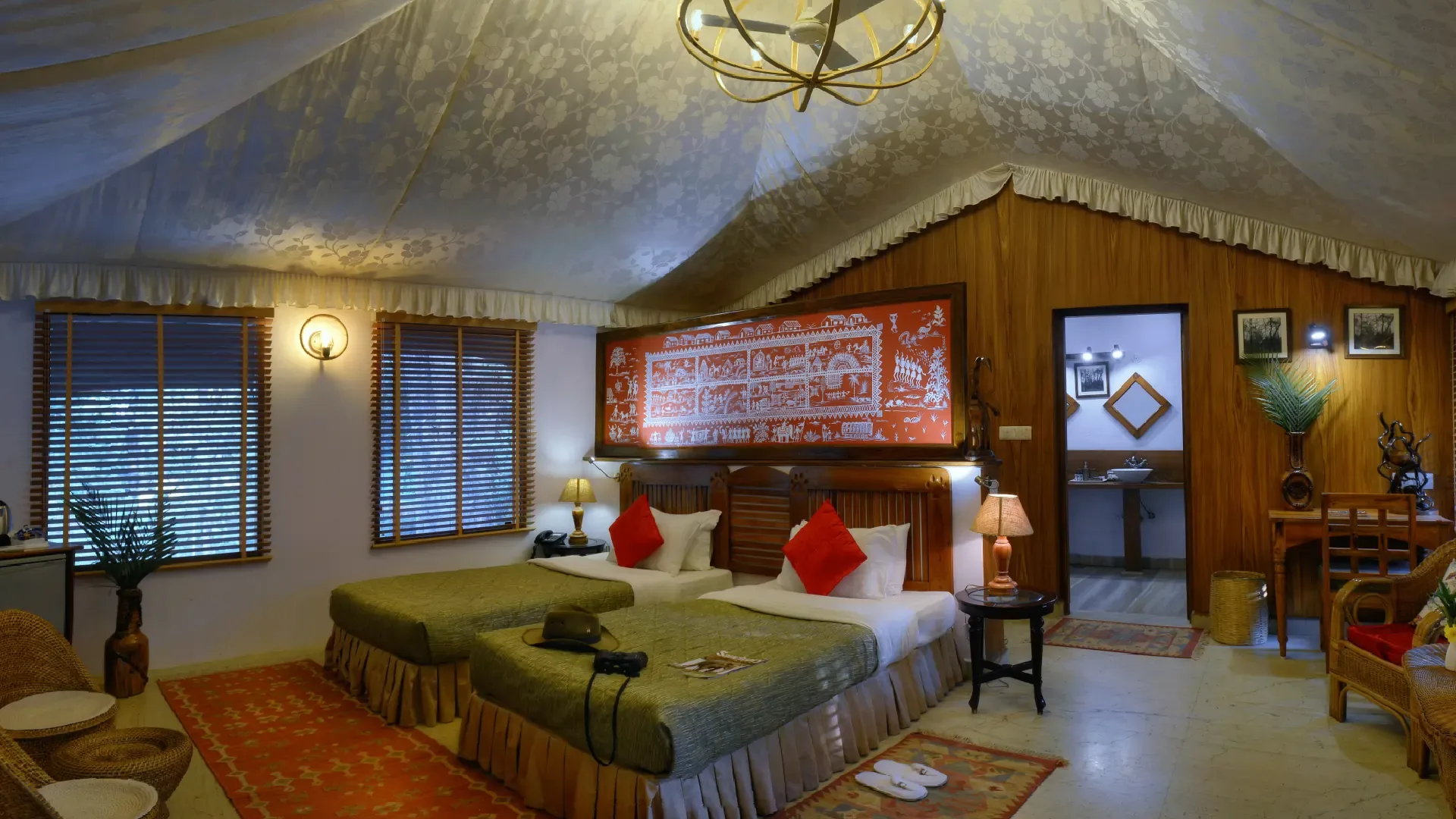Spacious luxury safari tent with twin beds and a carved headboard at a jungle camp near Pench