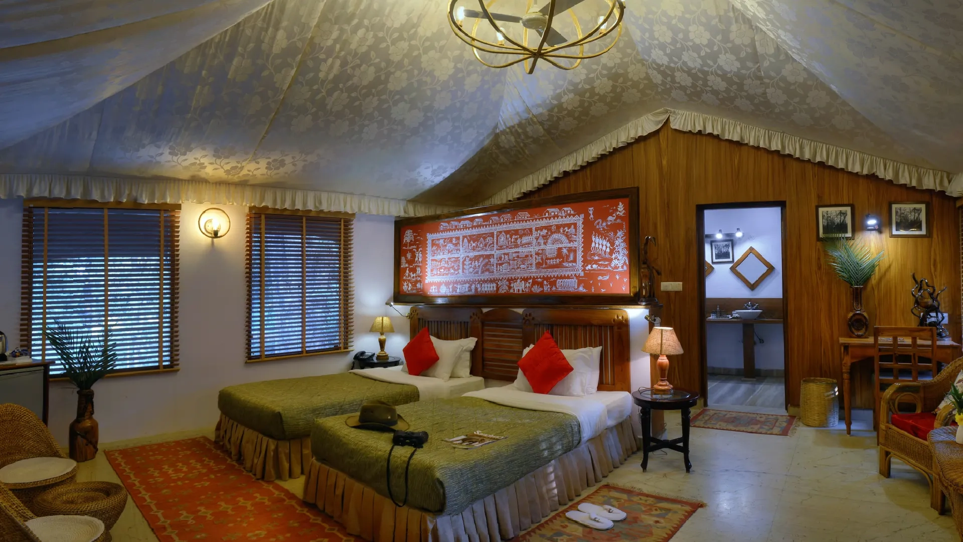 Spacious luxury safari tent with twin beds and a carved headboard at a jungle camp near Pench