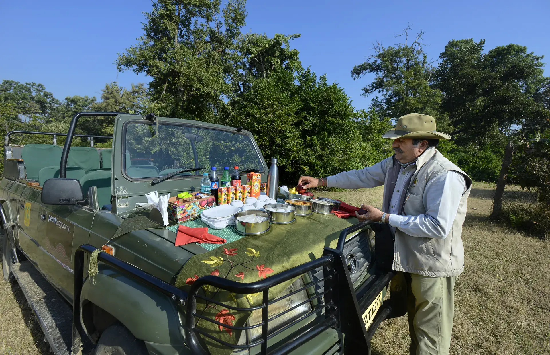 Naturalist briefing guests beside a safari Gypsy