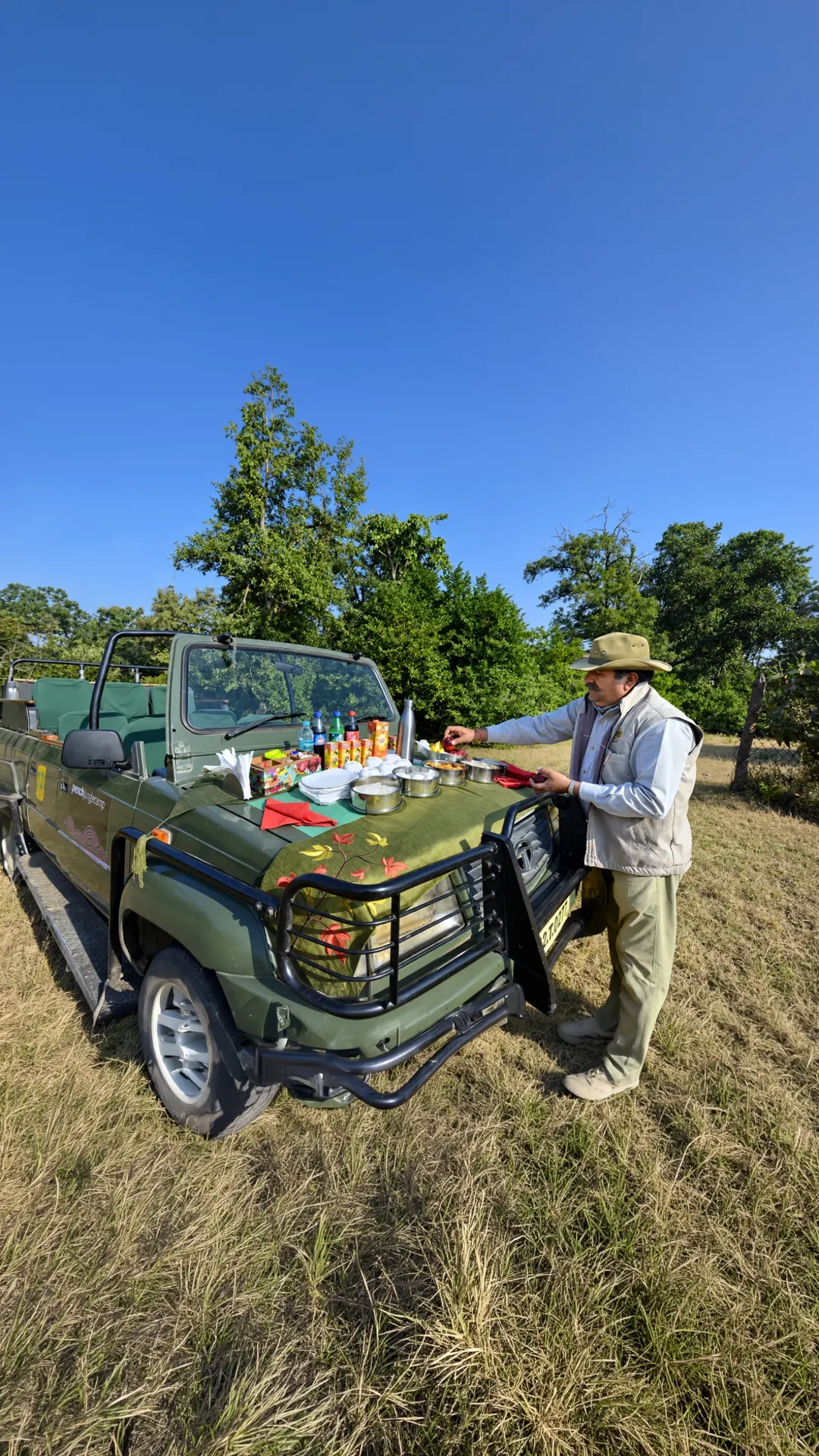 Bush breakfast laid out on the bonnet of a safari jeep in the forest
